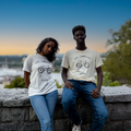 Two people wearing matching t-shirts with bicycle designs sitting on a stone wall.
