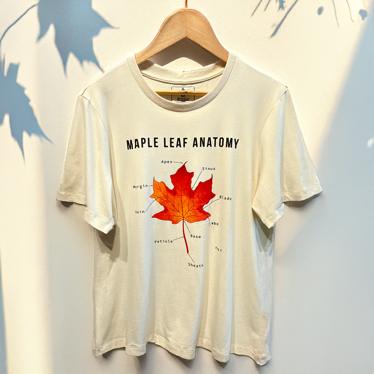 Natural beige sustainable t-shirt by VELU featuring a red maple leaf illustration labeled “Maple Leaf Anatomy.” Made in Canada from a bamboo rayon and cotton blend.