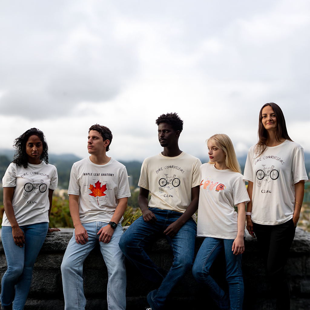 Five models wearing VELU’s “United in Vision” collection — featuring Bike Connoisseurs Club, Maple Leaf Anatomy, and Love in Hands t-shirts — standing in front of a Canadian landscape. Ethically made in Vancouver.